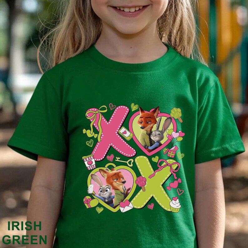 Peut inclure: Un t-shirt &agrave; manches courtes vert irlandais avec une impression graphique des personnages Nick Wilde et Judy Hopps de Zootopie. Le motif pr&eacute;sente de grandes lettres roses et vert citron formant XOXO, orn&eacute;es de c&oelig;urs, rubans et friandises.
