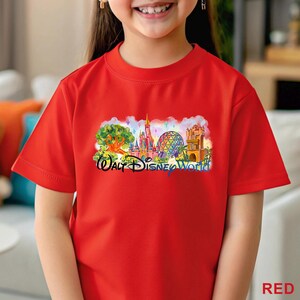 May include: A bright red short-sleeved t-shirt featuring a colorful graphic print of the Walt Disney World theme park landmarks, including the castle and geodesic sphere, with the text Walt Disney World printed in a dark blue script font.