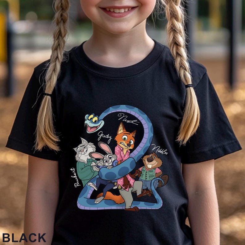 Puede incluir: Una camiseta negra con un estampado gr&aacute;fico de varios personajes animales animados, incluyendo un zorro, un conejo, un gato, un castor y una serpiente. El dise&ntilde;o incluye los nombres escritos a mano Pawbert, Judy, Nick y Nikkles cerca de los personajes.