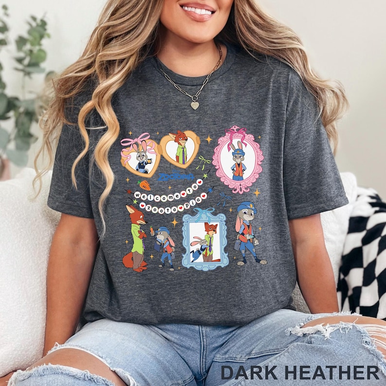 Pode incluir: Camiseta cinza escuro com personagens de desenhos animados em molduras decorativas e formatos de cora&ccedil;&atilde;o. A camisa tem o texto "WELCOME" em um design circular. A parte inferior da camisa tem o texto "DARK HEATHER".