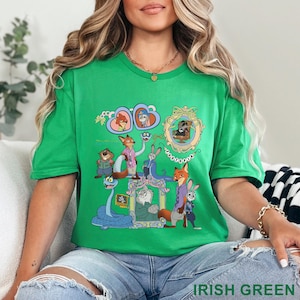 May include: Irish green t-shirt featuring a colorful graphic of cartoon characters. The design includes framed portraits and various animal figures. The word "ZOOTOPIA" is also visible in the design.