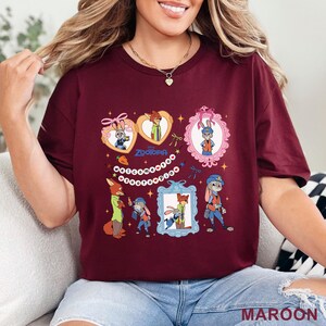 Pode incluir: Camiseta bord&ocirc; com personagens de Zootopia. O design inclui imagens de desenhos animados de Judy Hopps e Nick Wilde em v&aacute;rias molduras e poses. O texto "Zootopia" e "Welcome to Zootopia" tamb&eacute;m est&atilde;o presentes. A camiseta &eacute; feita de um material macio.