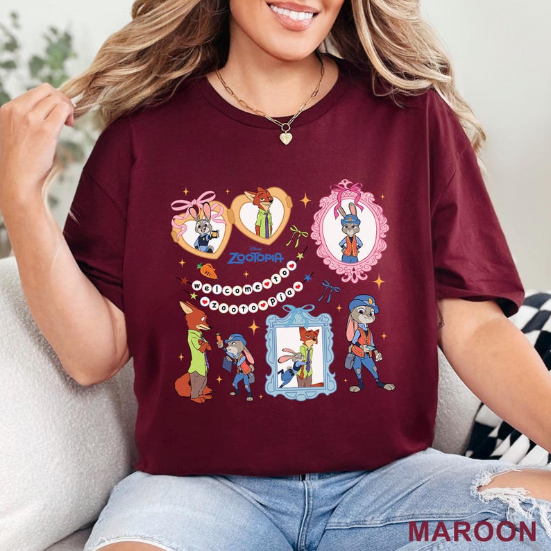 Pode incluir: Camiseta bord&ocirc; com personagens de Zootopia. O design inclui imagens de desenhos animados de Judy Hopps e Nick Wilde em v&aacute;rias molduras e poses. O texto "Zootopia" e "Welcome to Zootopia" tamb&eacute;m est&atilde;o presentes. A camiseta &eacute; feita de um material macio.