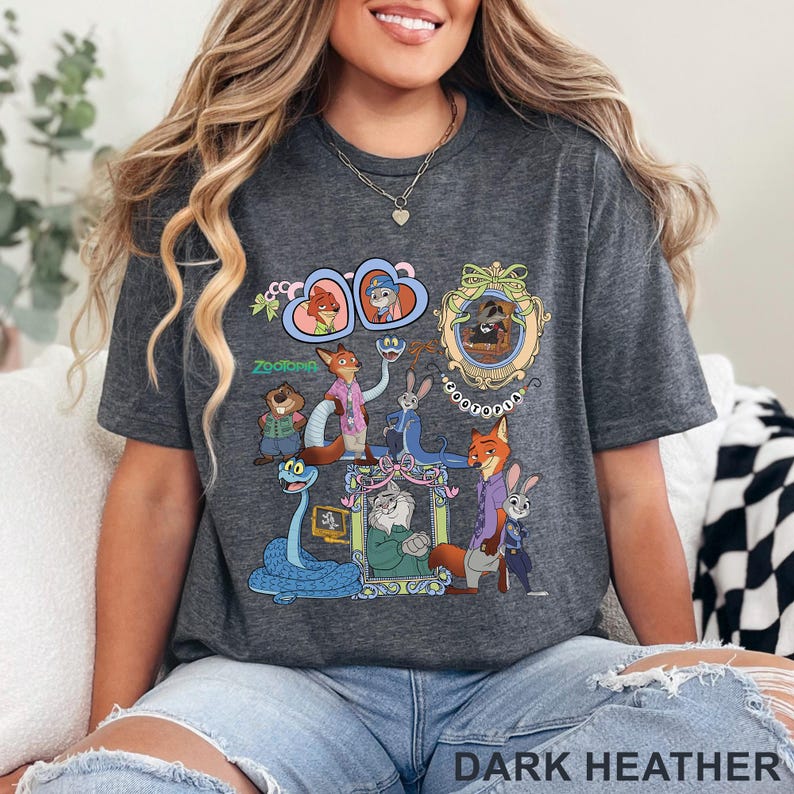 May include: Dark heather gray t-shirt featuring a colorful graphic of characters from the animated movie "Zootopia." The design includes various animal characters in detailed illustrations. The text "Zootopia" is also visible.
