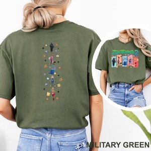 May include: Military green t-shirt featuring a colorful graphic of characters from Zootopia 2 on the front and back. The back design is a vertical arrangement of cartoon characters and icons. The front of the shirt has the text "Zootopia 2".