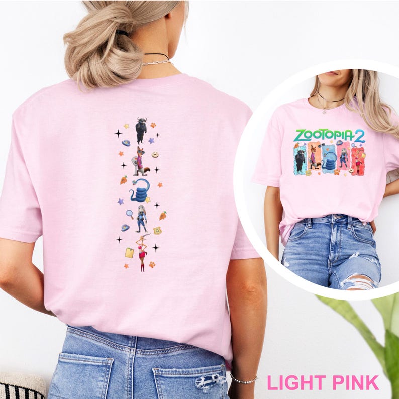 May include: Light pink t-shirt featuring the text "ZOOTOPIA 2" and character illustrations. The back of the shirt has a vertical design with character illustrations and stars. The shirt is made of a soft material.