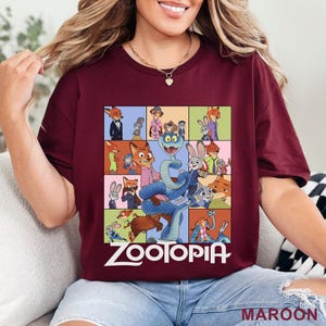May include: A maroon short-sleeve t-shirt featuring a grid of various cartoon characters from the movie Zootopia, including a large blue snake in the centre. The word Zootopia is printed in white text at the bottom of the graphic design.