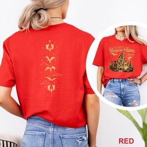 May include: Red t-shirt featuring a gold dragon design on the back and a castle graphic on the front. The front graphic includes the text "Riorson House" and "Castle". The shirt has a crew neck and short sleeves.