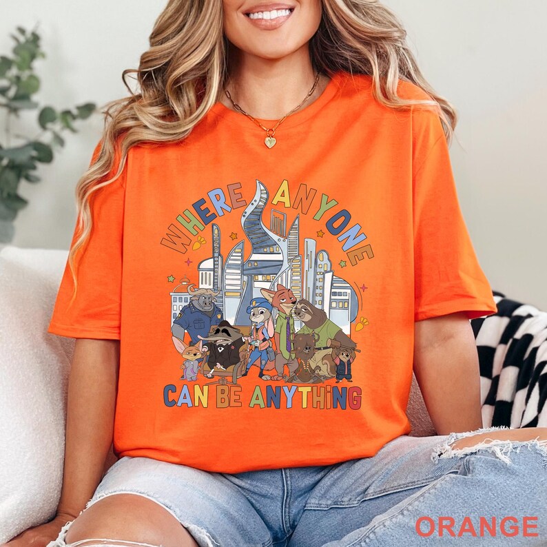 May include: Orange t-shirt with the text "WHERE ANYONE CAN BE ANYTHING" above a cartoon illustration of animal characters and a cityscape. The word "ORANGE" is at the bottom of the shirt.