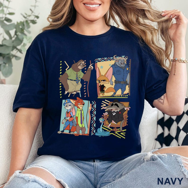 May include: Navy blue t-shirt with a colourful graphic of characters from the animated film Zootropolis. The design includes images of a sloth, fox, bunny, and other characters in a square pattern. The word "NAVY" is printed at the bottom.