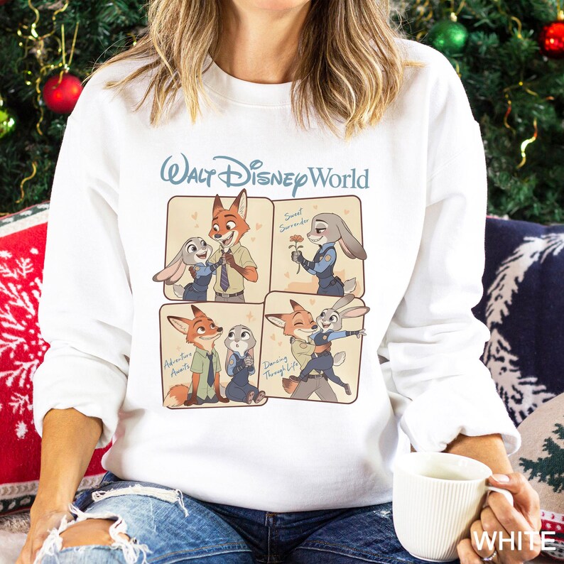 Puede incluir: Sudadera blanca con un gr&aacute;fico de Walt Disney World. El dise&ntilde;o presenta im&aacute;genes de dibujos animados de un zorro y un conejo. Las palabras "Walt Disney World" est&aacute;n en azul claro. Las im&aacute;genes muestran a los personajes en varias poses.