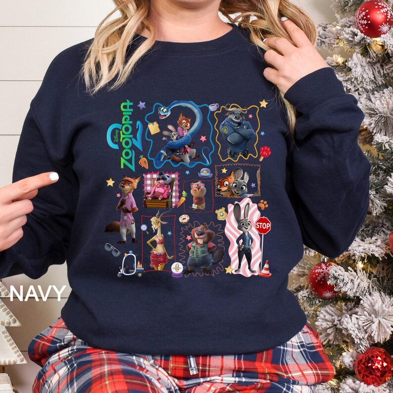 May include: Navy blue sweatshirt featuring a colorful graphic of characters from the animated film Zootopia. The design includes various characters in a grid layout, with the word "Zootopia" in green. The word "NAVY" is printed on the bottom left.