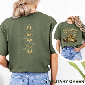 May include: Military green t-shirt with a gold dragon design on the back and a castle graphic with the text "Riorrson House" on the front. The shirt is a short-sleeved, crew neck style.