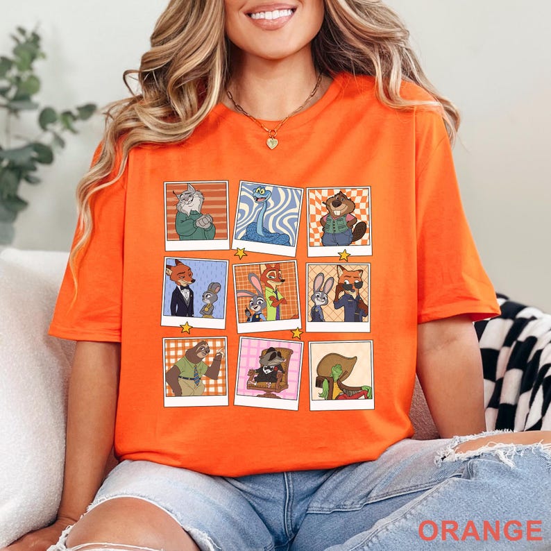 Pode incluir: Camiseta laranja brilhante com uma grade de retratos de personagens de desenhos animados em estilo Polaroid retr&ocirc;. Os personagens incluem uma raposa de terno, um coelho, uma pregui&ccedil;a e outros. A palavra "ORANGE" &eacute; impressa na parte inferior.