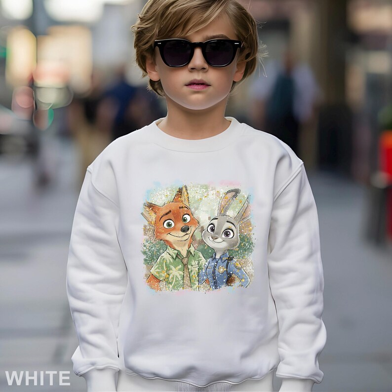Puede incluir: Sudadera blanca con un gr&aacute;fico colorido de Nick Wilde y Judy Hopps de Zootopia. La sudadera tiene cuello redondo y mangas largas. La palabra "WHITE" est&aacute; impresa en la parte inferior.