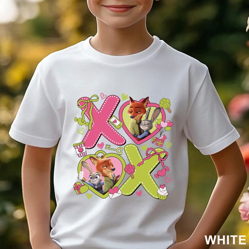 Peut inclure: Un t-shirt blanc &agrave; manches courtes avec une impression graphique des personnages Nick Wilde et Judy Hopps. Le motif comprend de grandes lettres roses et vertes formant XOXO, des c&oelig;urs, des petits cadeaux et des friandises autour des personnages.