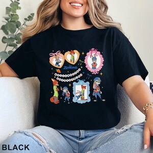 Pode incluir: Camiseta preta com um design de desenho animado colorido com personagens do filme Zootopia. O design inclui retratos emoldurados dos personagens, o t&iacute;tulo do filme e elementos decorativos. A palavra "BLACK" est&aacute; impressa na parte inferior.