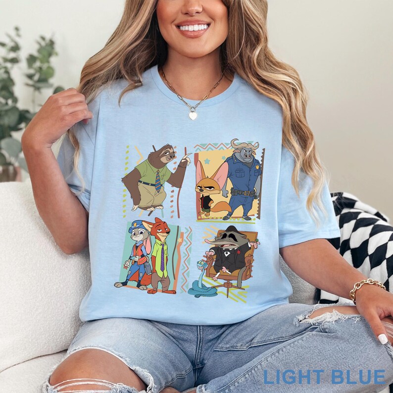 May include: Pale blue t-shirt with a cartoon graphic of Zootopia characters. The design features Judy Hopps, Nick Wilde, Flash, and others in a square arrangement. The text "LIGHT BLUE" is visible at the bottom of the image.