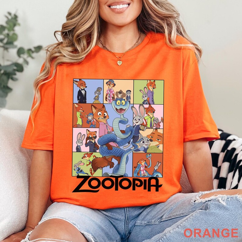 May include: A bright orange short-sleeve t-shirt featuring a grid of various cartoon characters from the movie Zootopia, including a large blue snake in the centre. The word Zootopia is printed in bold black lettering at the bottom of the graphic.