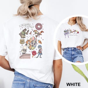 May include: A white t-shirt featuring a back graphic with various cartoon characters, a badge, a donut, and a carrot, along with the text "You can be whatever you wish to be." The front chest area displays a smaller graphic of character ears.