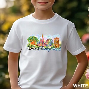 May include: A white short-sleeved t-shirt featuring a colorful graphic print of the Walt Disney World theme park landmarks, including the castle, the geodesic sphere, and the tree of life, with the text Walt Disney World printed in blue.