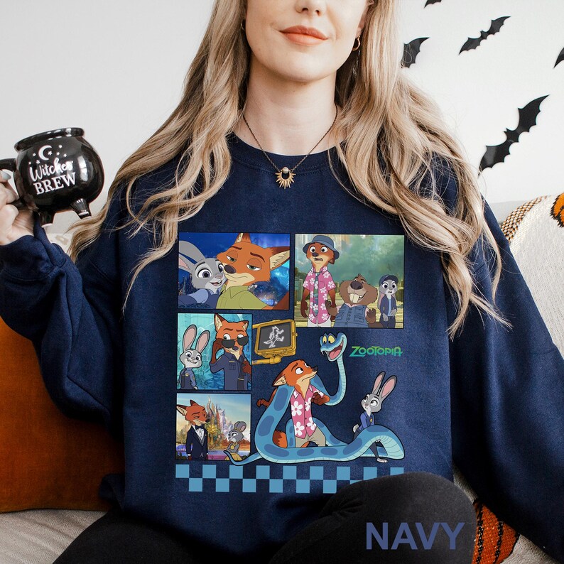 May include: Navy blue sweatshirt featuring a colorful collage of characters from the animated movie "Zootopia." The design includes images of Nick Wilde, Judy Hopps, and other characters. The word "Zootopia" is printed in green. The word "NAVY" is printed at the bottom.