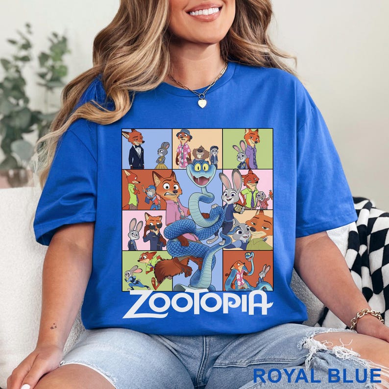 May include: A royal blue t-shirt featuring a grid of various Zootopia character illustrations, including Nick Wilde and Judy Hopps, with a large blue snake in the centre and the white Zootopia logo printed at the bottom of the graphic design.