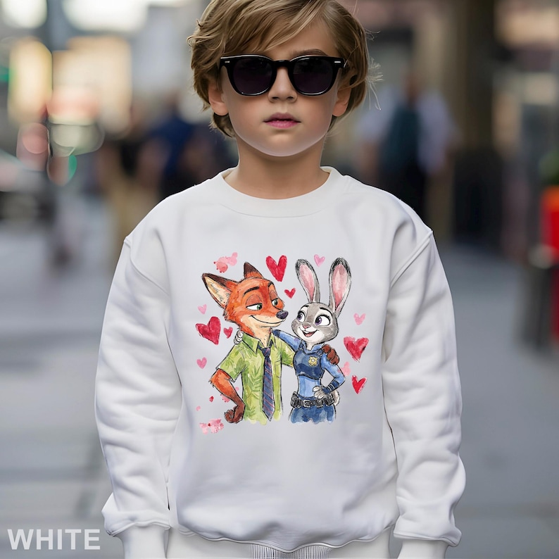 May include: White sweatshirt with a colourful illustration of Nick Wilde and Judy Hopps from Zootopia, surrounded by pink hearts. The word "WHITE" is printed at the bottom. The sweatshirt is worn by a person wearing sunglasses.