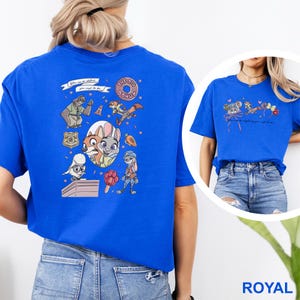 May include: A royal blue t-shirt featuring a large graphic on the back with various Zootopia characters, including a sloth, a fox, and a rabbit, alongside a donut and text. The front chest area displays a smaller graphic with mouse ears and text.