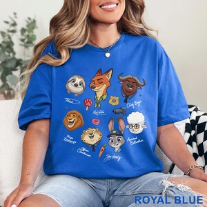 Puede incluir: Una camiseta azul real con un estampado gr&aacute;fico de varios personajes animados de Zootopia, incluidos Nick Wilde, Judy Hopps, Flash, Chief Bogo, Mayor Lionheart, Officer Clawhauser y Bellwether, junto con sus nombres y peque&ntilde;os iconos.