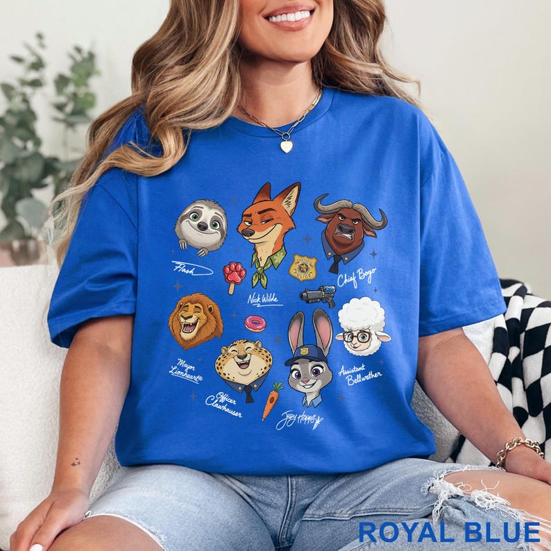 Puede incluir: Una camiseta azul real con un estampado gr&aacute;fico de varios personajes animados de Zootopia, incluidos Nick Wilde, Judy Hopps, Flash, Chief Bogo, Mayor Lionheart, Officer Clawhauser y Bellwether, junto con sus nombres y peque&ntilde;os iconos.