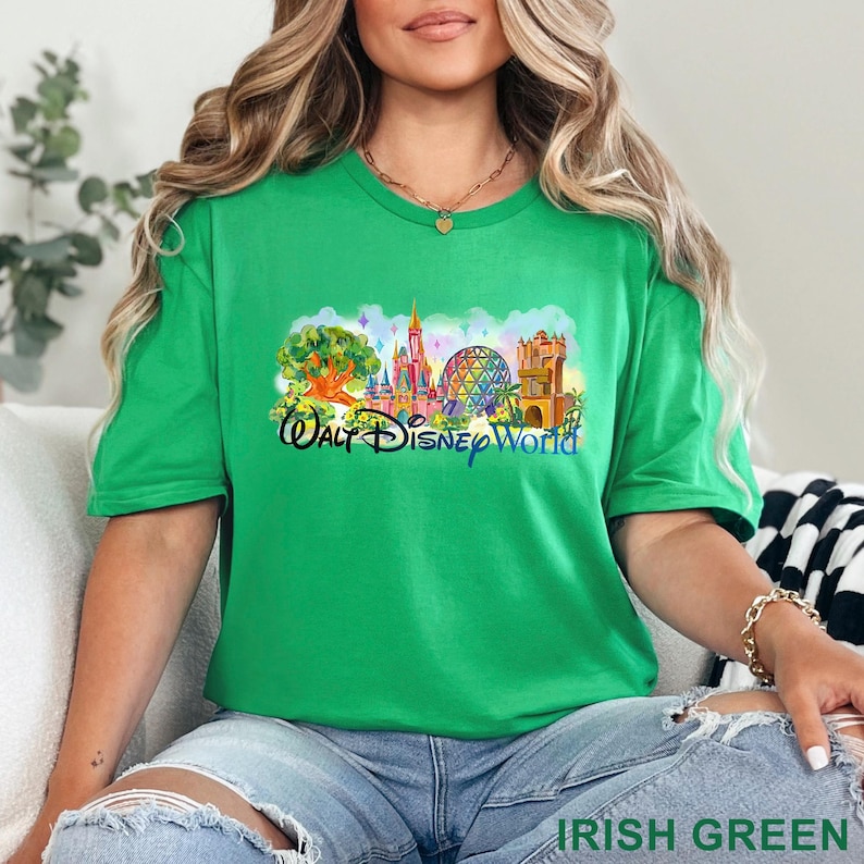 May include: A bright Irish green short-sleeve t-shirt featuring a colorful graphic of the Walt Disney World skyline, including the castle, the Epcot sphere, and the Tree of Life, with the text Walt Disney World printed in black script below.