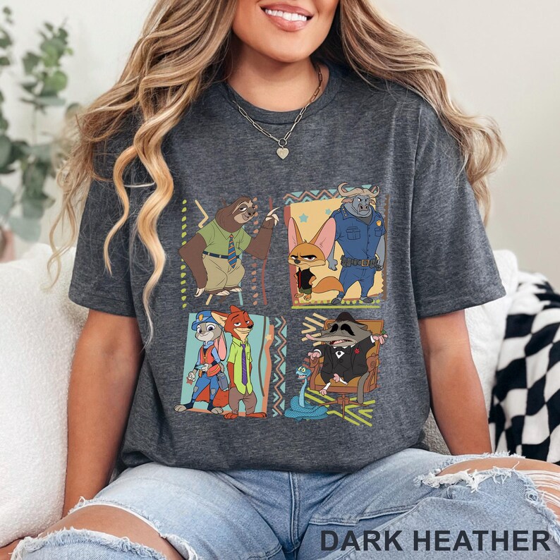 May include: Dark heather grey t-shirt with a vibrant graphic of Zootopia characters. The design showcases a sloth, fox, and buffalo, among others. The text "DARK HEATHER" is printed at the bottom of the shirt.