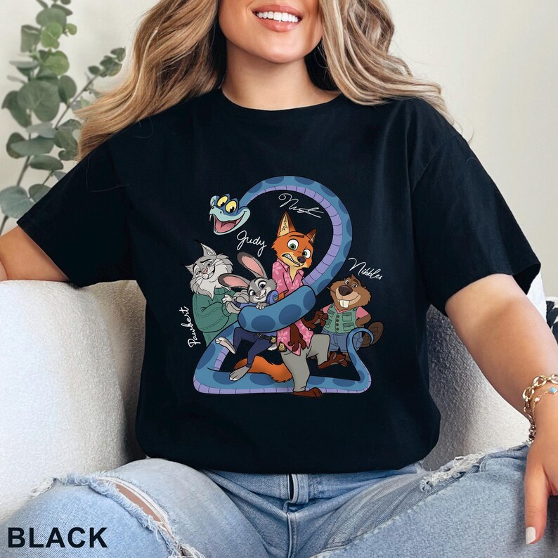 Puede incluir: Una camiseta negra con un estampado gr&aacute;fico de varios personajes animados, incluyendo un zorro, un conejo, un gato, un castor y una serpiente. El dise&ntilde;o incluye los textos Pawbert, Judy, Nick y Nibbles escritos en estilo cursivo.