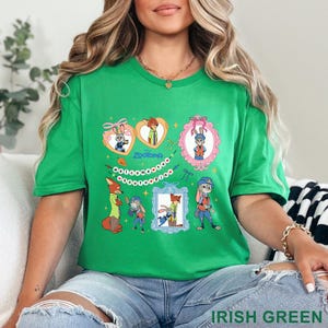 Pode incluir: Camiseta verde irland&ecirc;s com personagens de desenhos animados de Zootopia. O design inclui imagens de uma raposa e um coelho em v&aacute;rias molduras e formatos de cora&ccedil;&atilde;o, com a palavra "Zootopia". O texto "IRISH GREEN" est&aacute; na parte inferior.