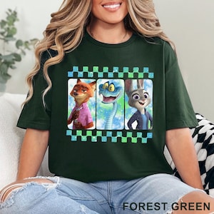 May include: Forest green t-shirt featuring three cartoon characters in a film strip design. The characters include a fox in a pink shirt, a blue snake, and a rabbit in a blue jacket. The shirt is made of a soft material.