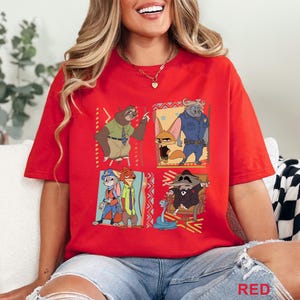 May include: A red t-shirt with a vibrant graphic of characters from the animated film Zootropolis. The design includes a sloth, fox, buffalo, rabbit, and raccoon. The word "RED" is printed at the bottom right corner of the shirt.