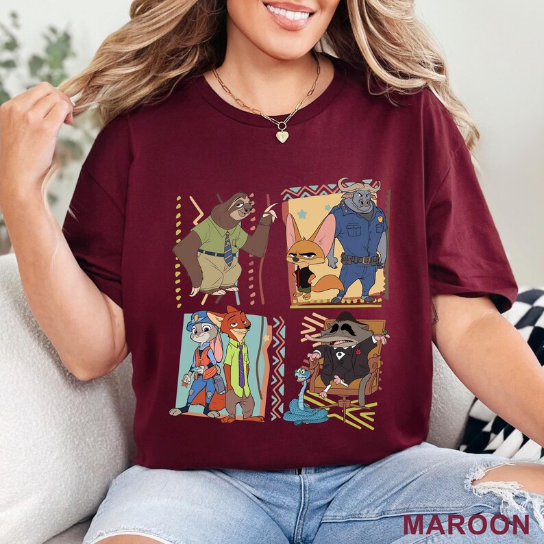 May include: Maroon t-shirt with a colourful graphic of animated film characters. The design features a sloth, fox, and other animal characters in a square grid. The word "MAROON" is printed at the bottom of the shirt.
