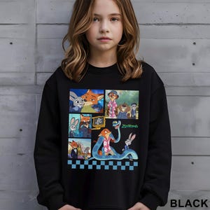 May include: Black sweatshirt featuring a colorful graphic of characters from the animated movie Zootopia. The design includes images of a fox, a bunny, and other characters. The word "Zootopia" is also visible. The sweatshirt is worn by a young person.