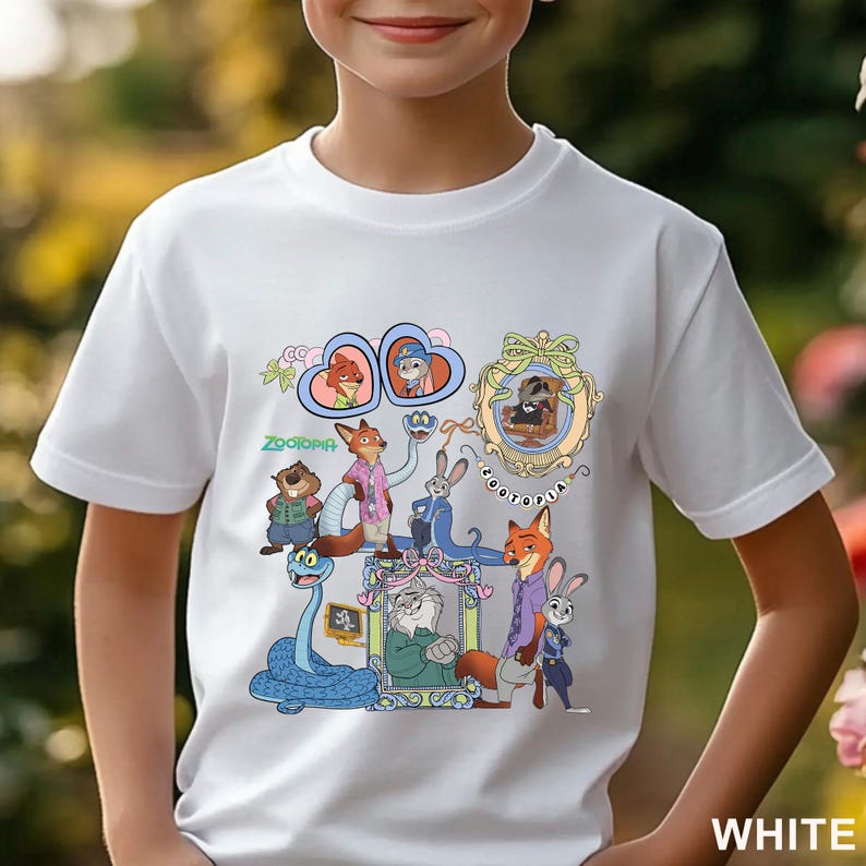 May include: White t-shirt featuring a colorful graphic of characters from the animated movie Zootopia. The design includes various animal characters in a cartoon style, with the word "Zootopia" in green. The word "WHITE" is printed at the bottom.