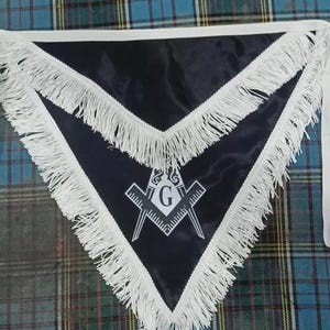 May include: A black Masonic sash with white fringe and a white embroidered compass and square with a 'G' in the center.