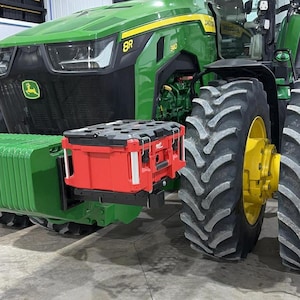 May include: A green and yellow John Deere tractor with large black tires. A red Milwaukee toolbox is mounted on the front. The tractor has the number "8R" and "340" printed on it.