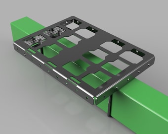 May include: A dark gray metal bracket with a rectangular shape and cut-out sections, resting on two bright green rectangular supports. The bracket has multiple holes and is designed for mounting or securing other components. The background is a light gray.