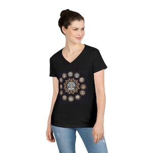 May include: Black V-neck t-shirt featuring a detailed, circular graphic. The graphic has a central image surrounded by ornate, golden-brown and white designs against a dark blue background. The shirt is made of a soft material.