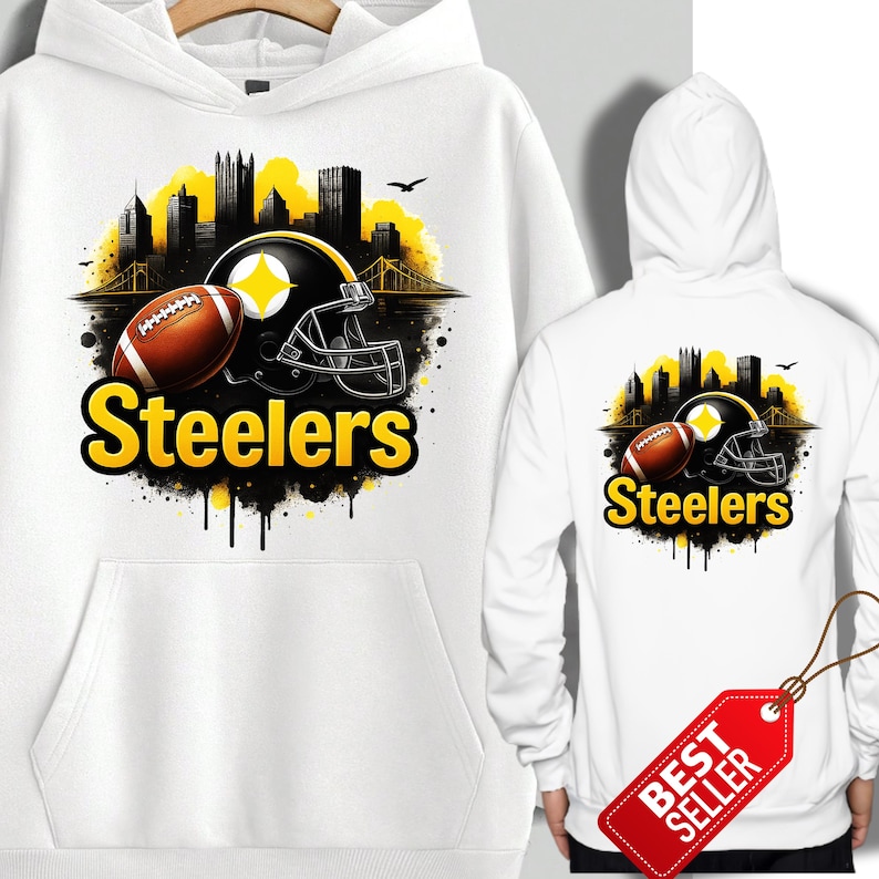K&ouml;nnte beinhalten: Wei&szlig;er Hoodie mit einer Grafik eines Footballs, Helms und Stadtbilds in Gelb und Schwarz, mit dem Wort "Steelers" in Gelb. Die R&uuml;ckseite des Hoodies hat ein &auml;hnliches Design. Ein rotes "Bestseller"-Etikett h&auml;ngt am Hoodie.
