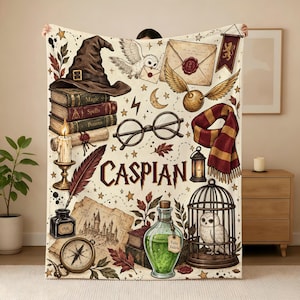 May include: A cream-colored throw blanket featuring a magical theme with illustrations of a wizard hat, books, a white owl, a golden snitch, glasses, a scarf, a candle, a quill, an inkwell, a map, a potion bottle labeled Felix Felicis, and a cage.