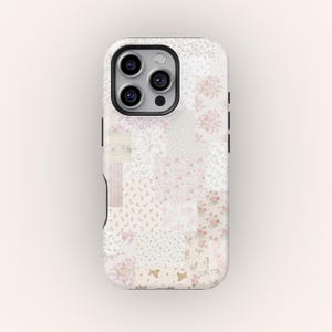 Pode incluir: Uma capa de telefone branca e preta com um design de patchwork. A capa apresenta uma variedade de quadrados florais e estampados em tons de rosa, creme e branco. A capa do telefone tem um módulo de câmera preto e botões laterais pretos.
