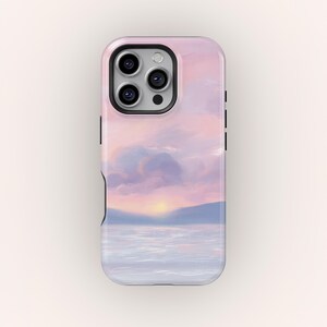 May include: A smartphone case with a pastel landscape painting of a sunset over water. The case has a pink and purple sky with blue mountains in the distance. The phone case has a black camera and button details.