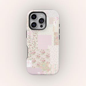 May include: A phone case with a patchwork design. The case features a variety of floral and gingham patterns in shades of pink, cream, and white. The case has a black camera lens and black side buttons.