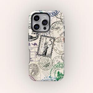 May include: A phone case decorated with a collection of vintage travel stamps in multiple colours. The stamps feature images of the Statue of Liberty, camels, and the Route 66 sign. The case has a cream-coloured background.